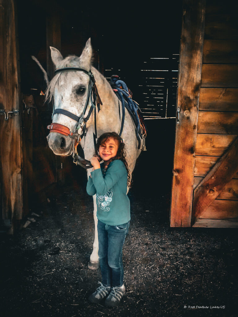 Girl smiling with pony, highlighting the joys of Getting Ready for a Trail Ride near Red Feather Lakes Colorado