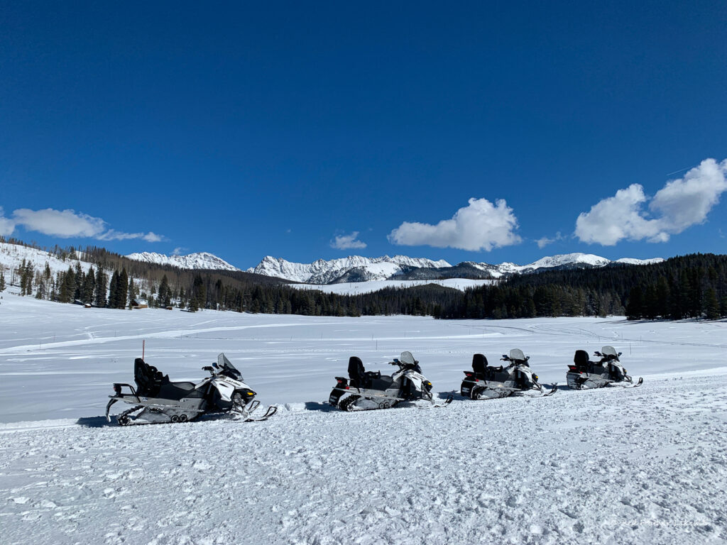 Snowmobiles on snowy mountain landscape under blue sky near Red Feather Lakes Colorado