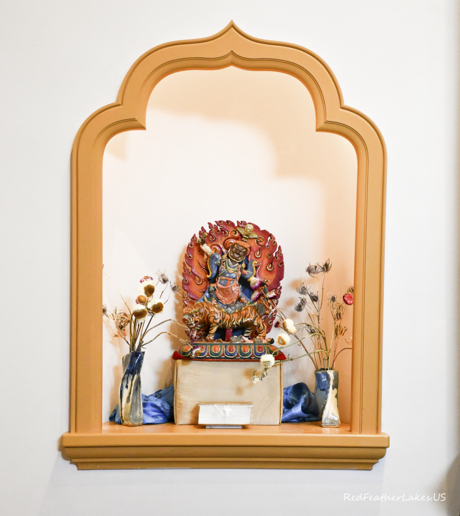 Colorful religious statue with dried flower decoration.