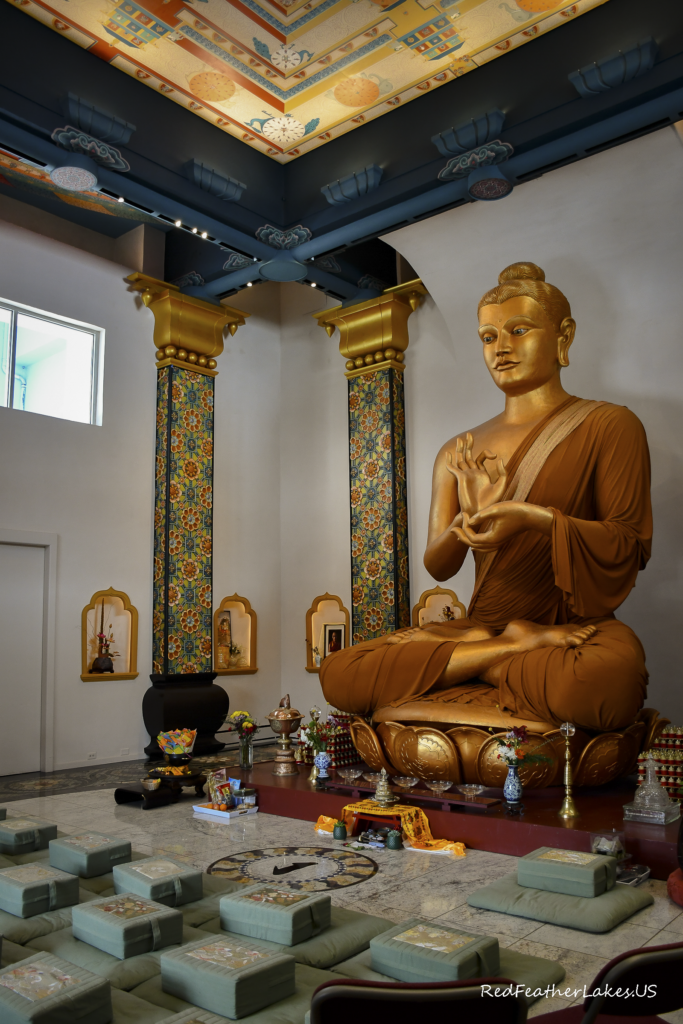 Golden Buddha statue in ornate temple with meditation mats.