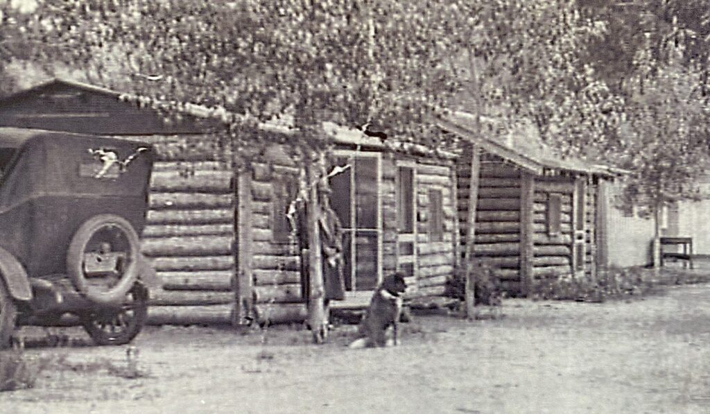 Vintage log cabins with dog and old car