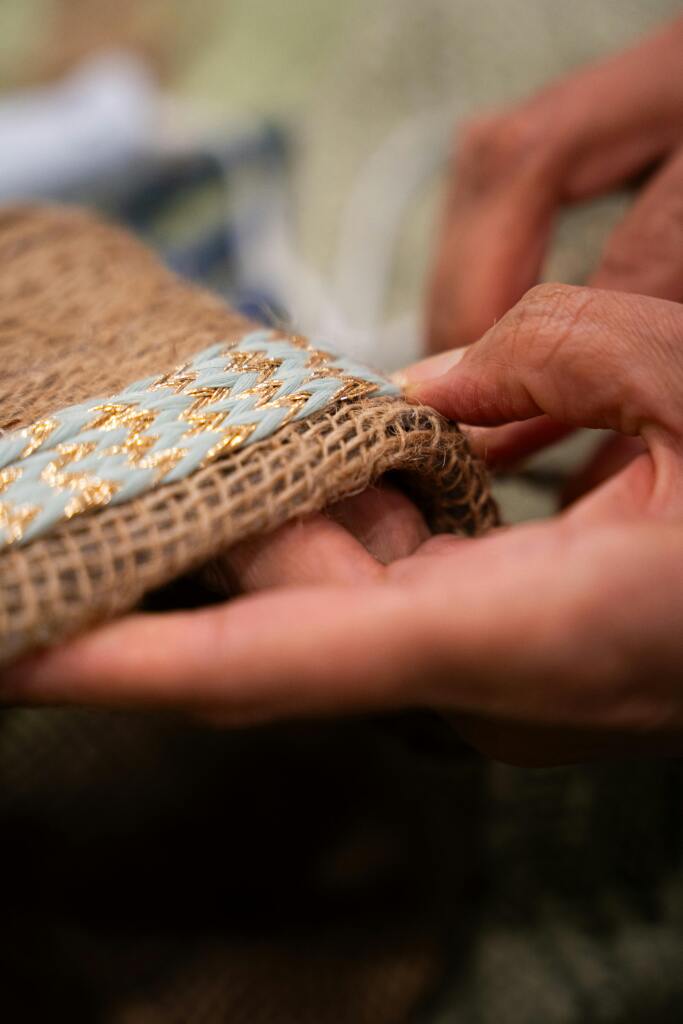 Detailed close-up of hands skillfully crafting a textured handmade fabric with intricate embroidery.