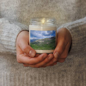 Hands holding lit candle with mountain label