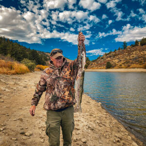 Man holding large trout by lakeside