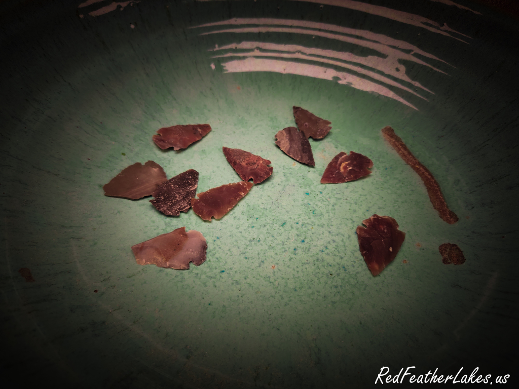 Hand-knapped stone arrowheads displayed in a green pottery bowl at the Trading Post Resort store