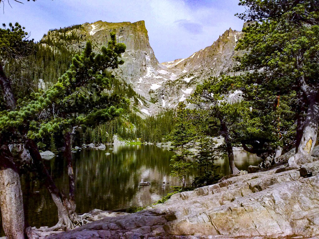 Hallett Peak rising above Dream Lake, seen across the water from the rocky shoreline, Rocky Mountain National Park