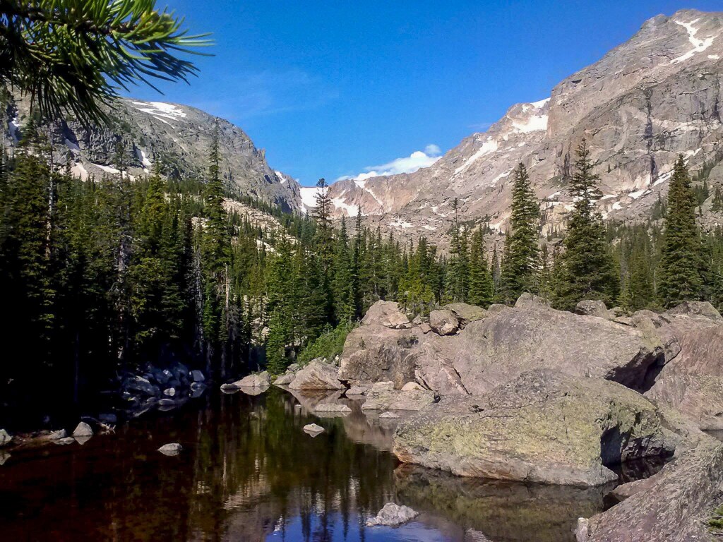Rounded granite boulders piled along the shore of Lake Haiyaha beneath snow-streaked cirque walls, Rocky Mountain National Park