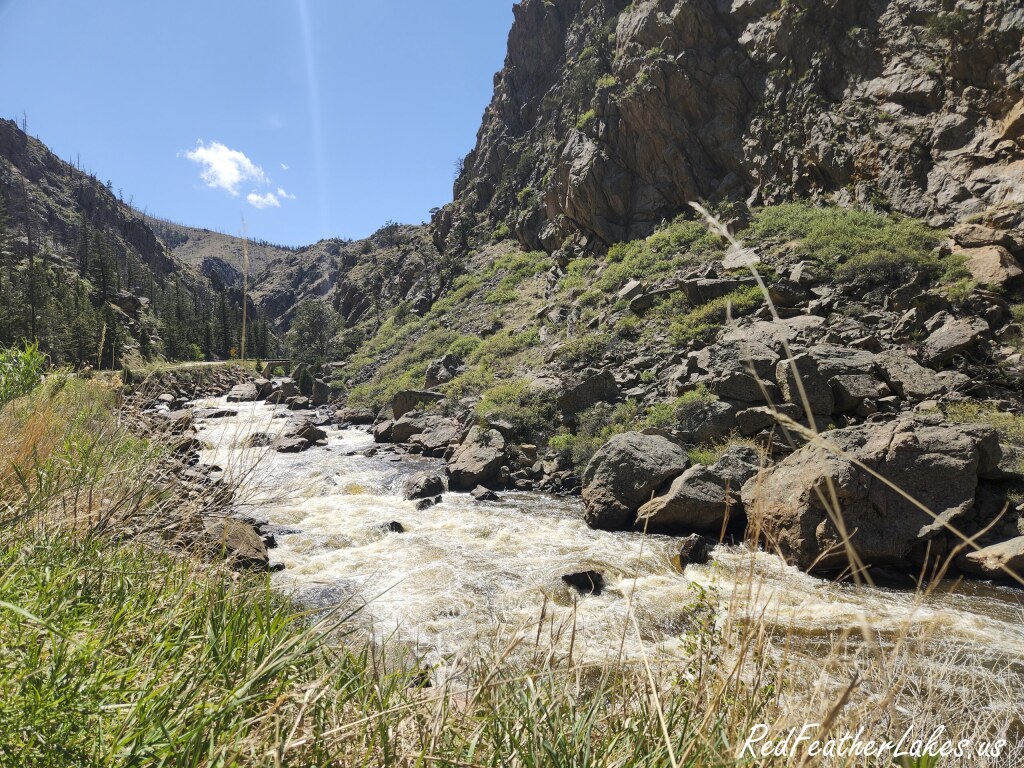 Whitewater rushing down the Cache la Poudre River between steep rock canyon walls in Poudre Canyon, Northwest Larimer County, Colorado